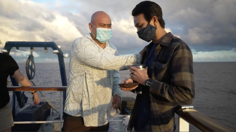 Two men stand together on an outer deck conducting protocol